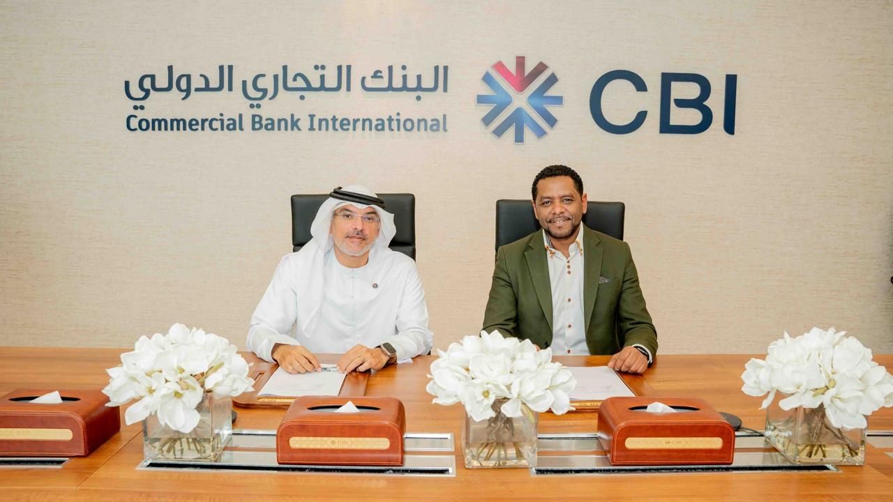 Michel Tzsfaldet seated and signing a partnership agreement beneath the Commercial Bank International (CBI) logo in Dubai.
